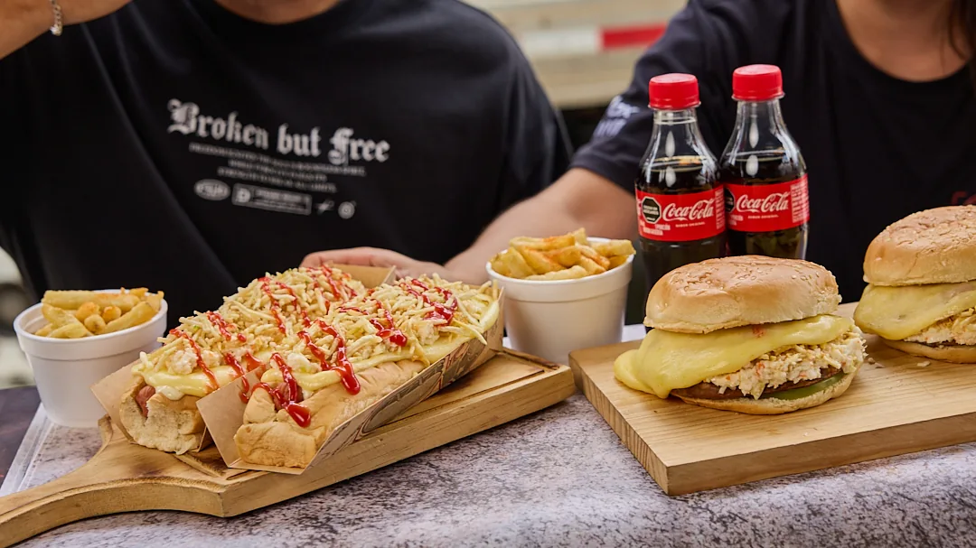 Dos clientes de Los Super compartiendo perro, hamburguesas, papas y gaseosas