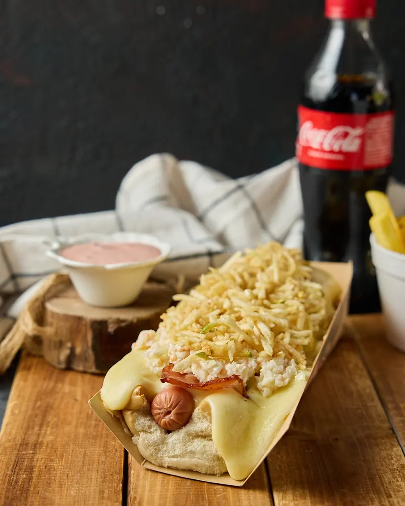 Perro grande servido sobre tabla de madera con salsas aparte